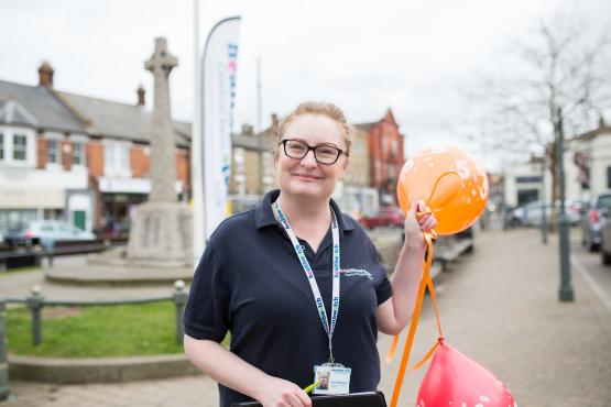 Woman stood outside holding balloons